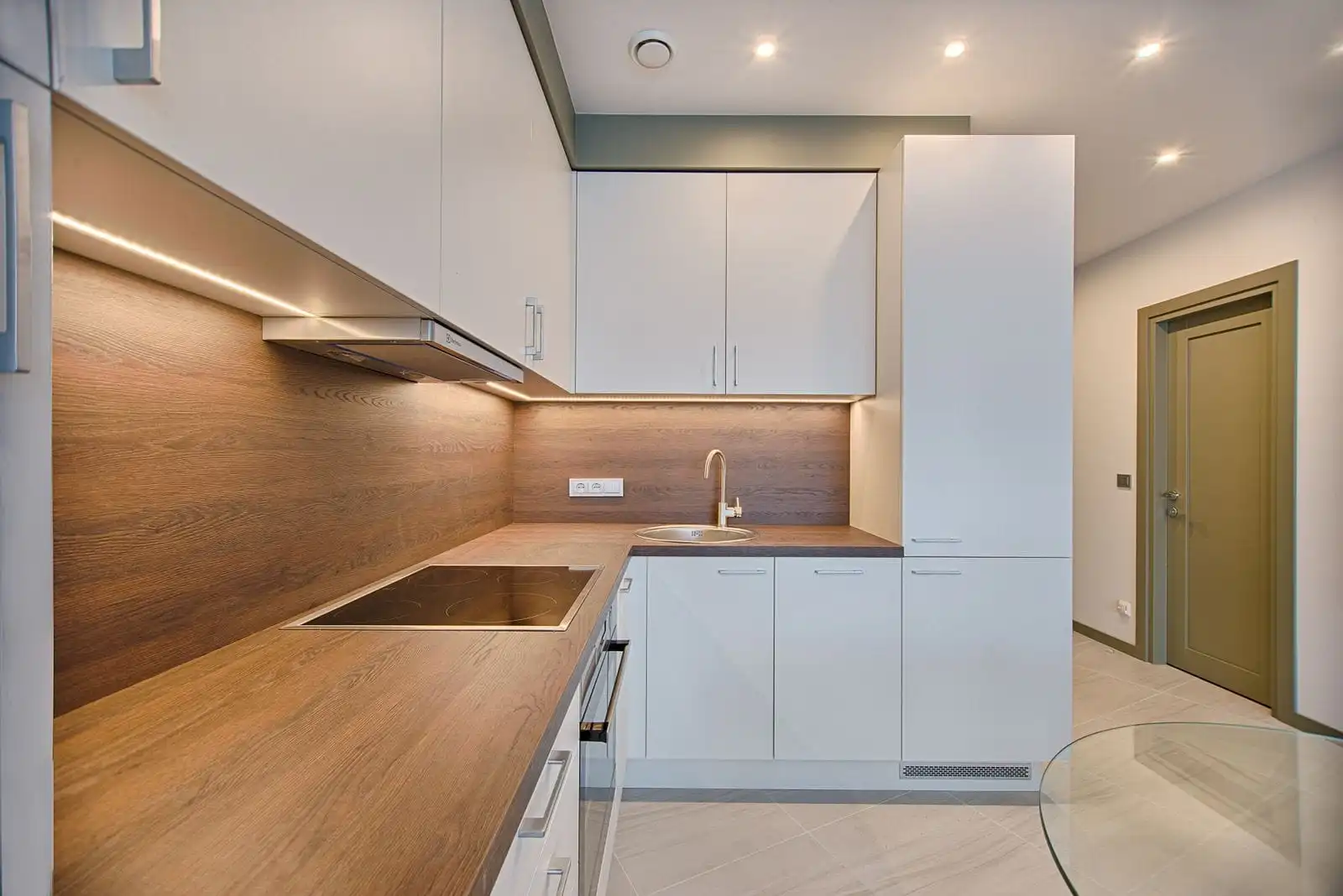 Modular kitchen with white cabinets, a warm timber worktop and under-cabinet lighting