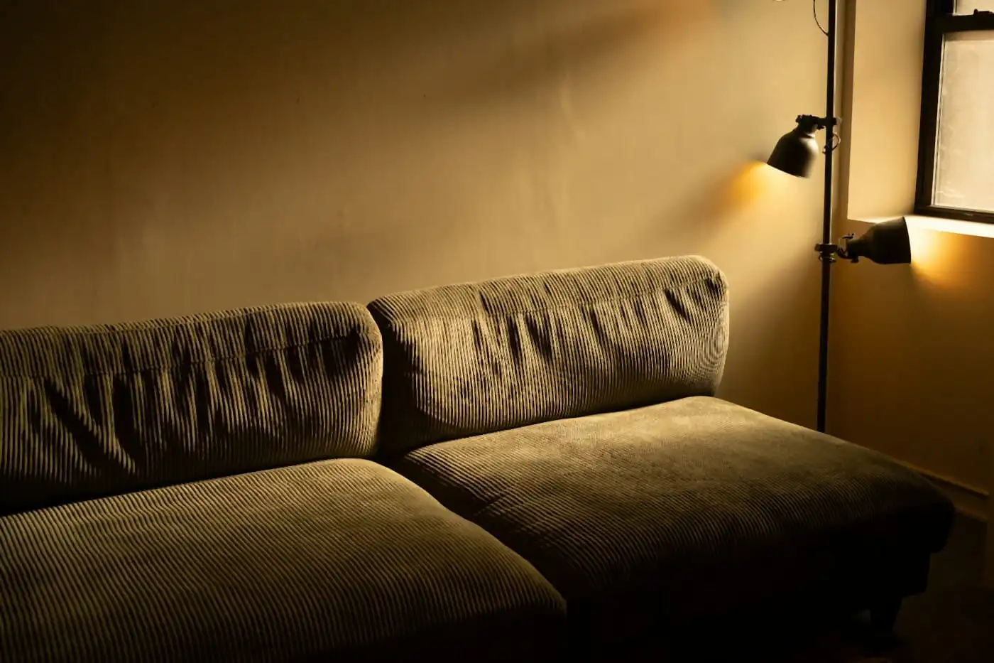 Warm evening light from a wall lamp falling over a sofa